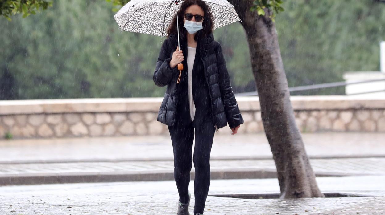 Una mujer con paraguas y mascara