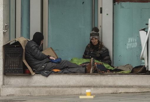 Una pareja descansa a las puertas de una sucursal bancaria, en la Milla de Oro