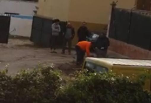 El alcalde y su hijo (de naranja) cortan leña este sábado ante la mirada de tres vecinos. Captura del vídeo que su autora quitó luego de las redes sociales