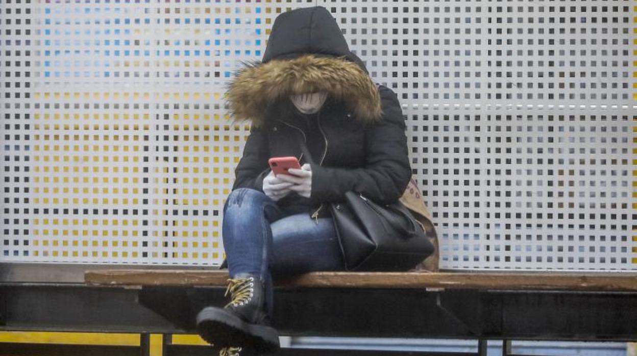 Una mujer con guantes y mascarilla espera el Metro en Valencia, este viernes