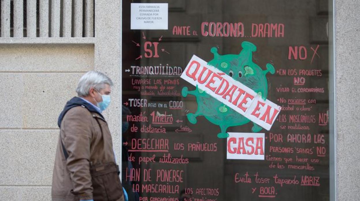 Un hombre pasa delante de un establecimiento con el mensaje Quédate en Casa, en Lugo