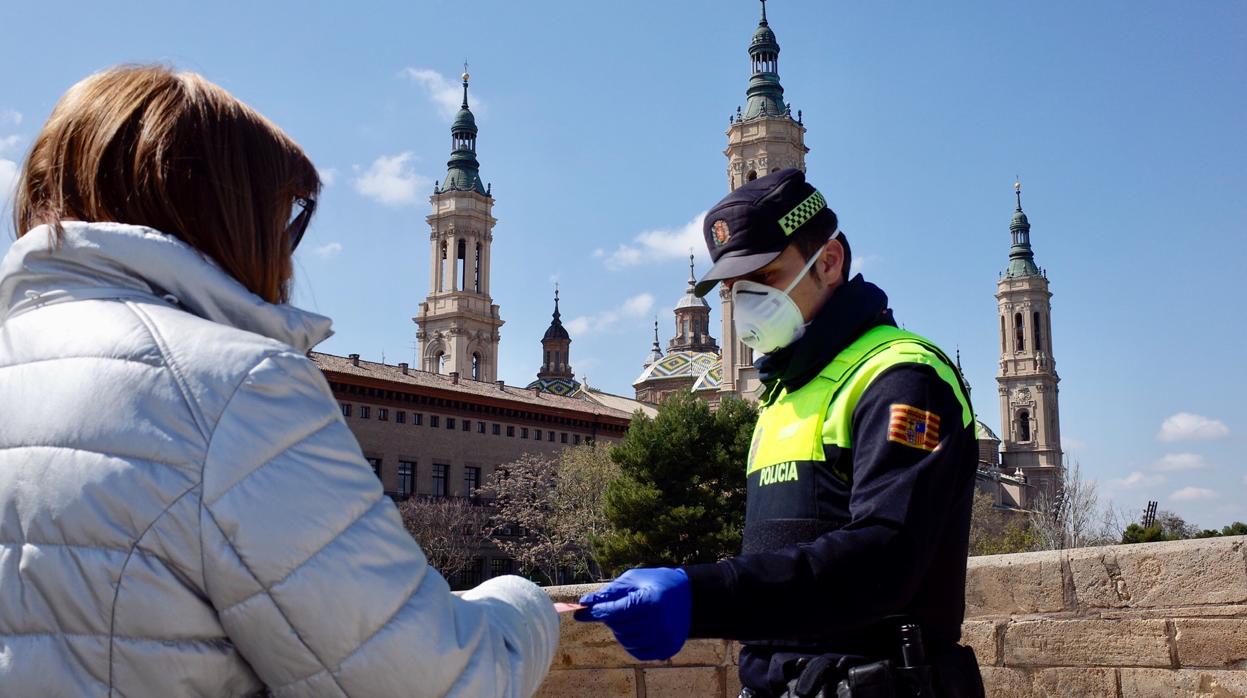 Un policía local pide la documentación en un control a una zaragozana, en un control por el coronavirus