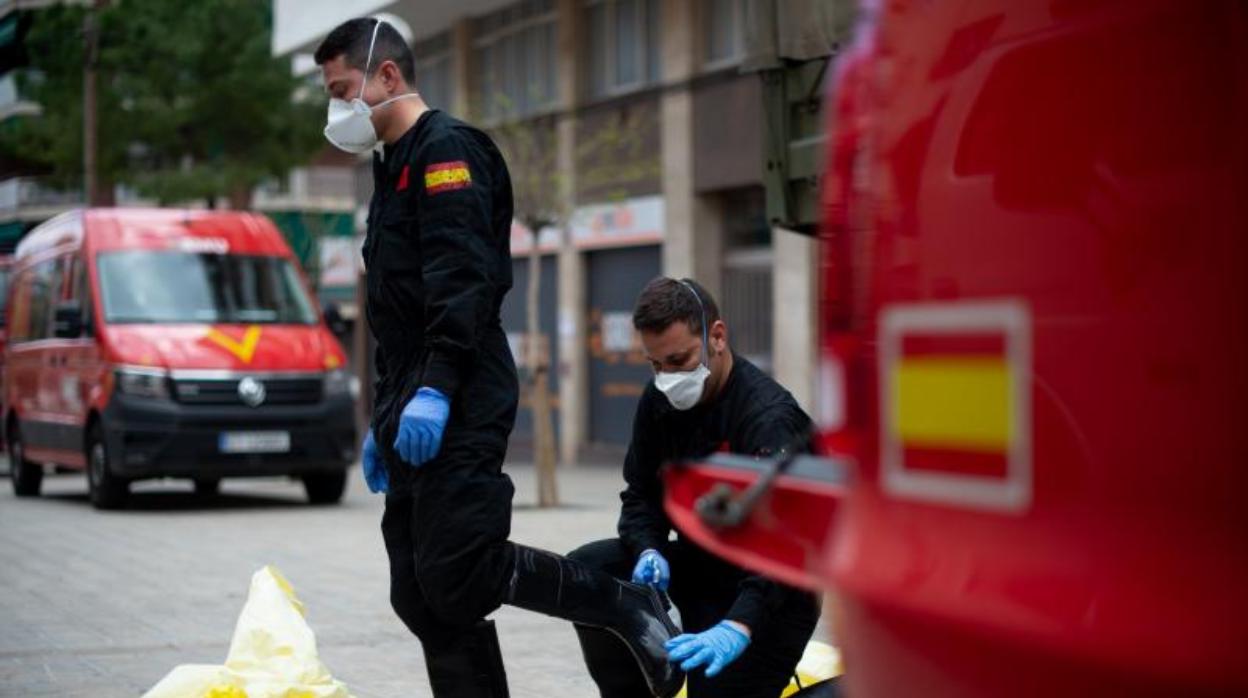 Dos miembros de la UME desinfectan su material tras operar en una residencia en Hospitalet, el viernes