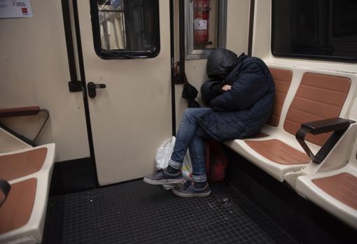 Un hombre duerme junto a sus enseres dentro de un vagón de la línea 1