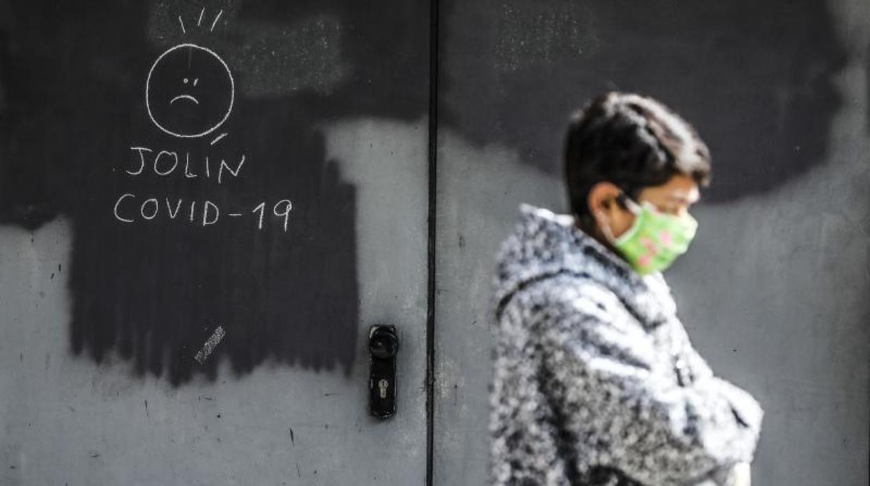 Una transeúnte pasa junto a dibujo sobre el Covid-19 en una calle de Valencia