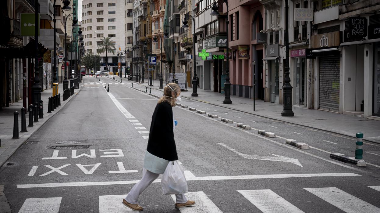 Una mujer, en una céntrica calle de valencia con todos los establecimientos cerrados