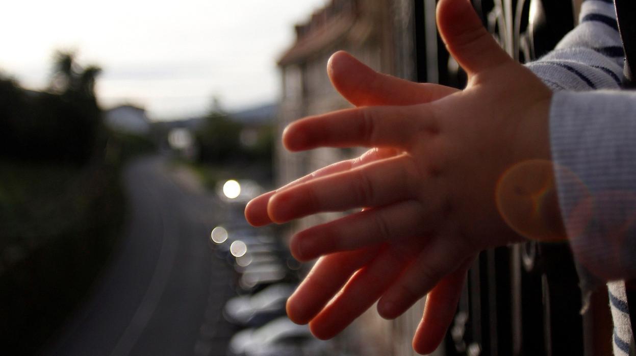 Un niño aplaude desde la terraza de su casa