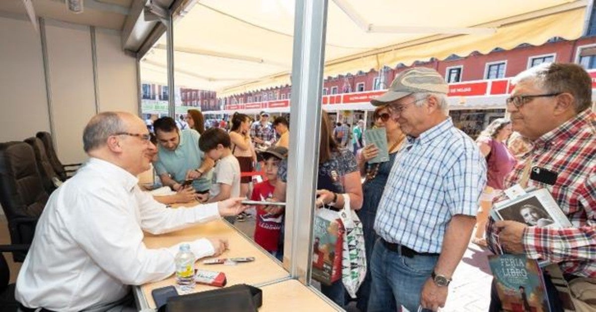 Gustavo Martín Garzo firma ejemplares de una de sus obras en una pasada edición de la Feria del Libro de Valladolid