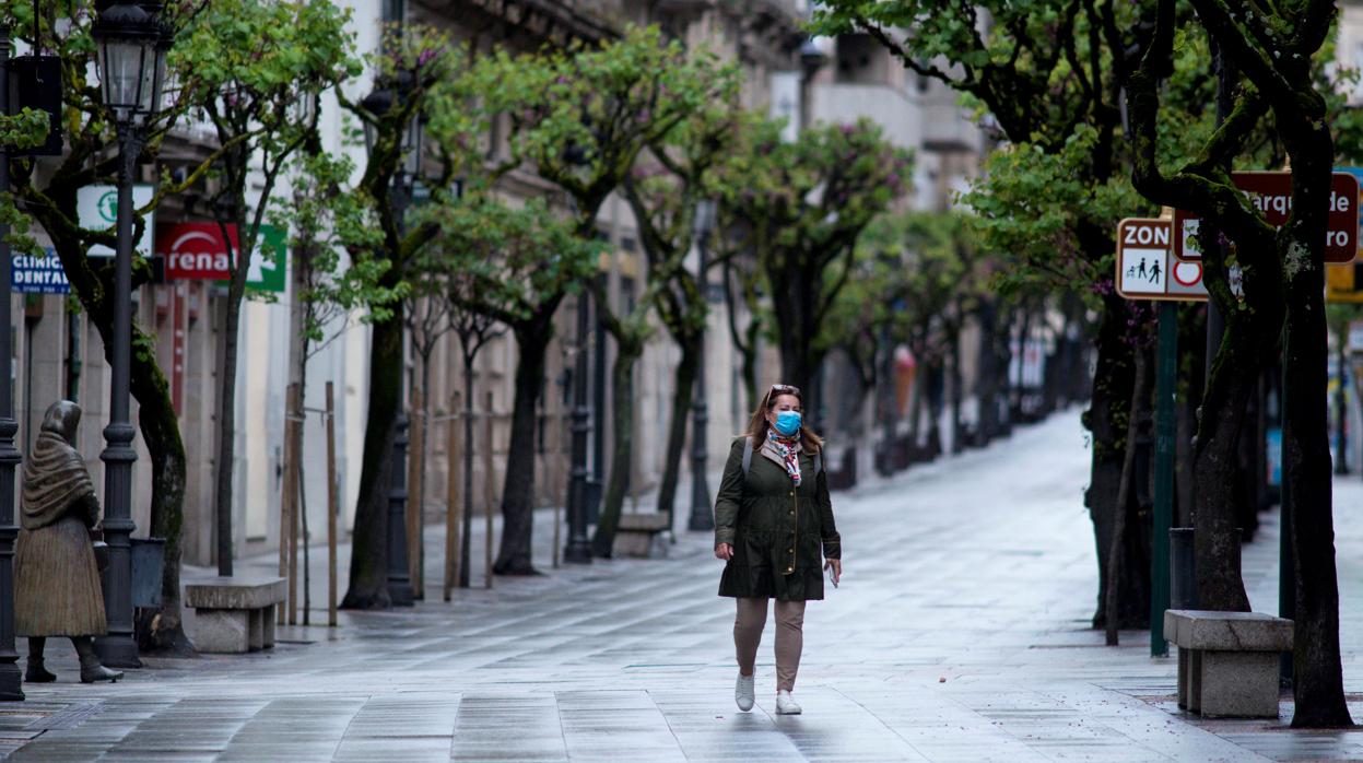 Una mujer protegida con una mascarilla camina por una céntrica calle de Orense, el pasado viernes