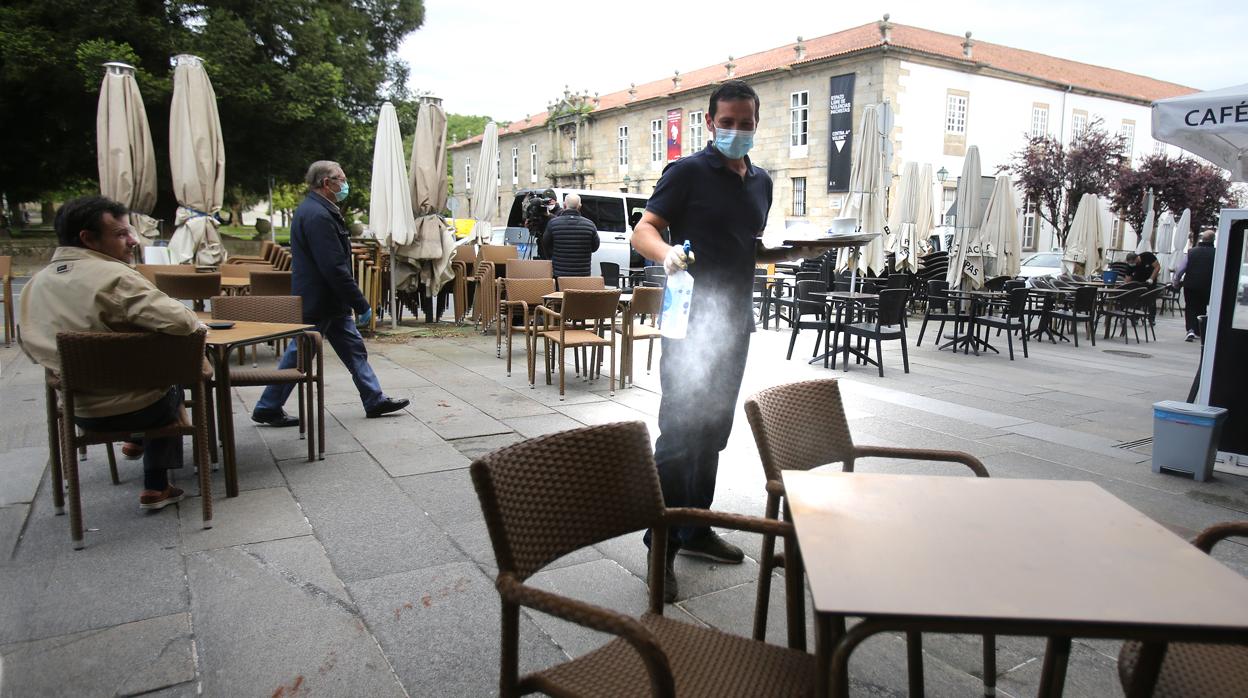 Un camarero desinfecta una mesa en una terraza de Santiago