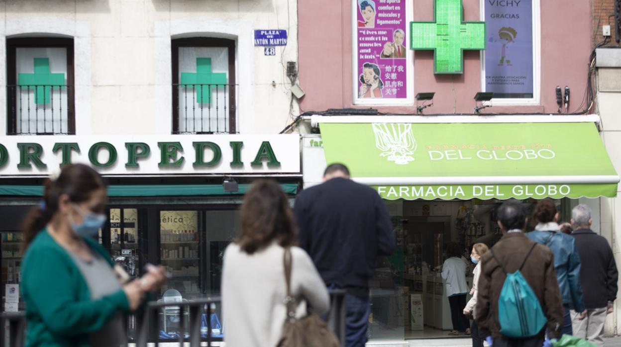 Varias personas hacen cola frente a una farmacia, en la plaza de Antón Martín