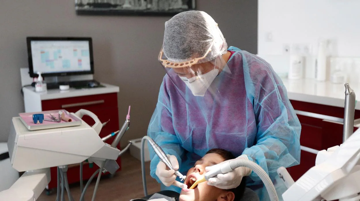 Un dentista atiende a un paciente a una clínica dental reabierta tras la pandemia