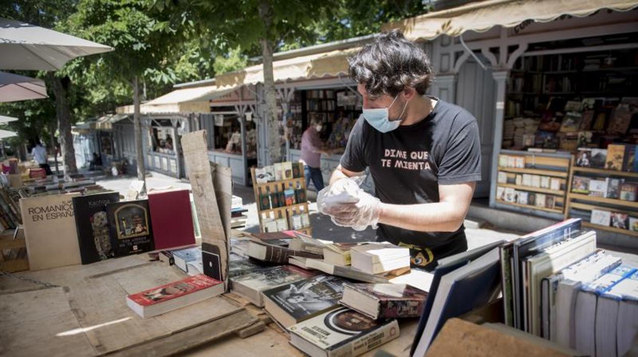 Los libreros de la Cuesta de Moyano, ayer, desinfectan y colocan los ejemplares con mascarillas y guantes