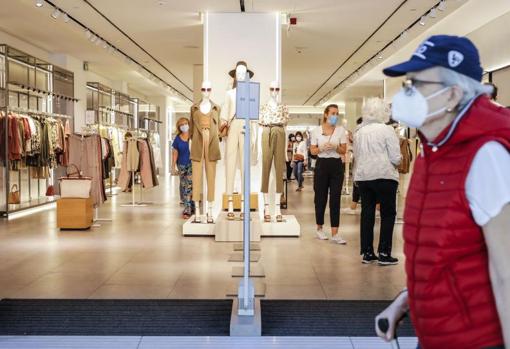 Un hombre pasa con mascarilla por la entrada de una tienda de ropa, tras su reapertura en la fase 1 de la desescalada en Valencia