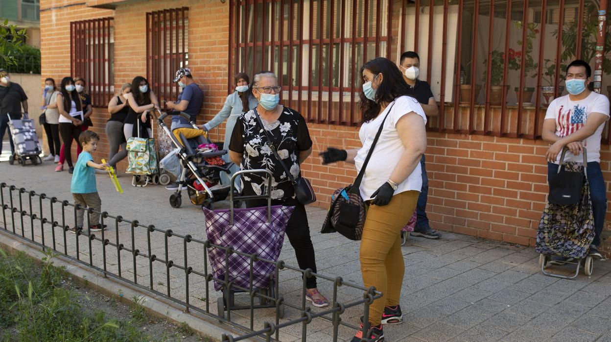 Varias personas hacen cola para recibir alimentos en la parroquia de San Juan de Dios, en Vallecas