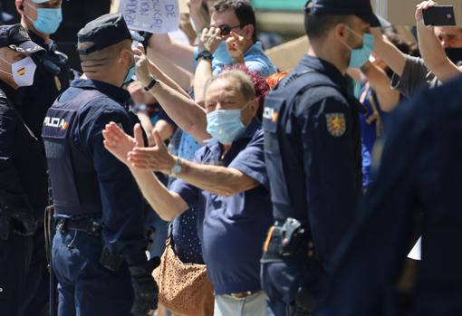 Un hombre se abre paso entre un cordón policial para aplaudir al paso de la caravana de vehículos contra el Gobierno de Pedro Sánchez