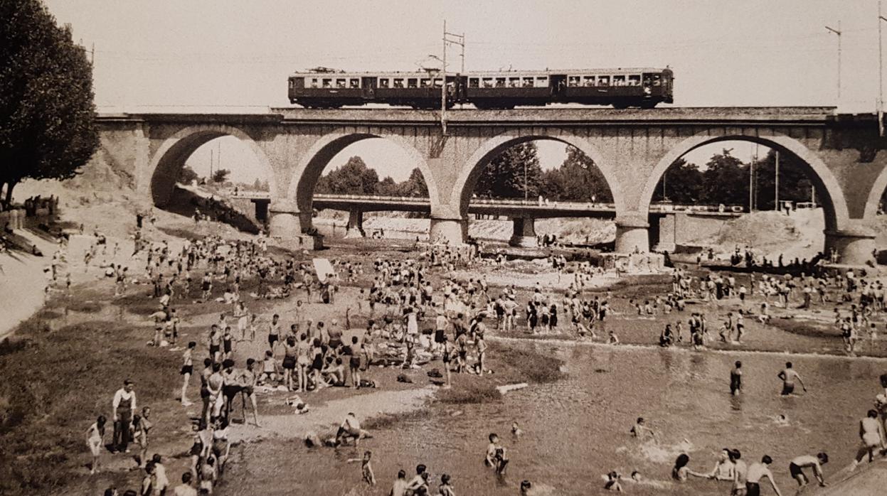 El tren sobre un río abarrotado de bañistas, retratado por Santos Yubero