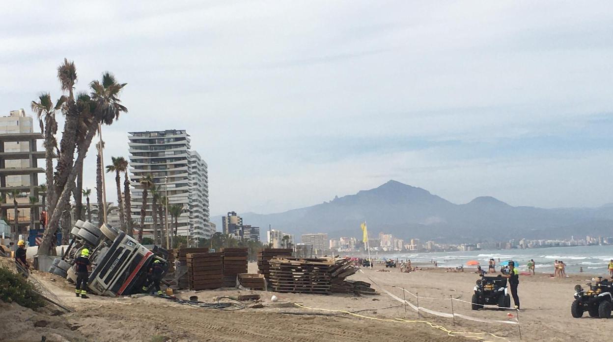 Efectivos de la Policía Local junto al camión volcado en la arena de la Playa de San Juan