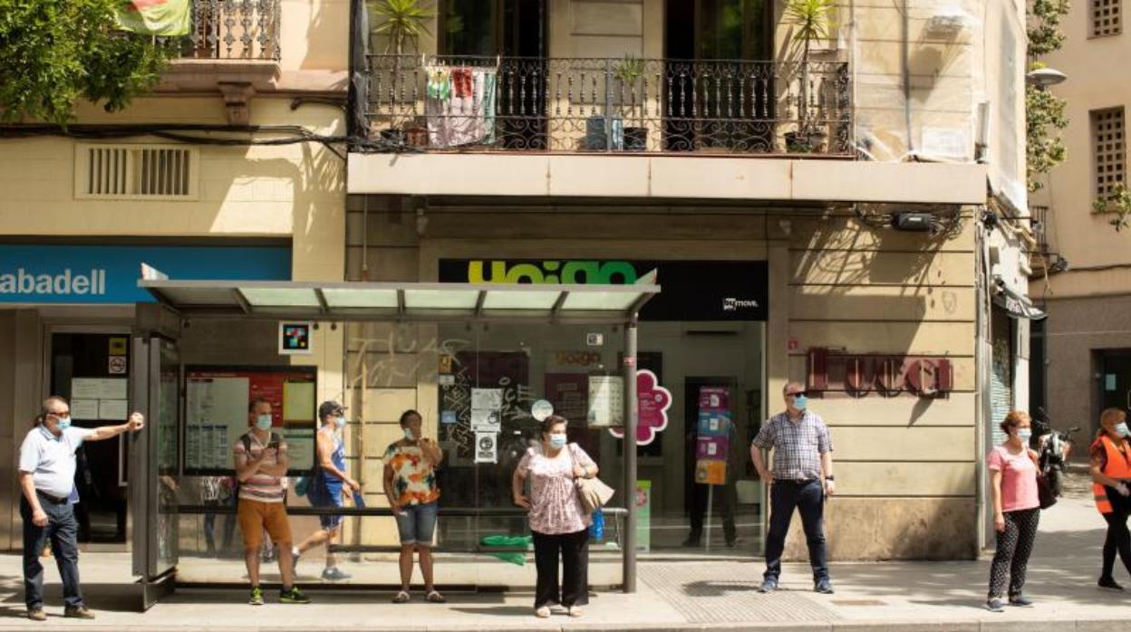 Varios usuarios del transporte público, esperando el bus esta semana en Barcelona