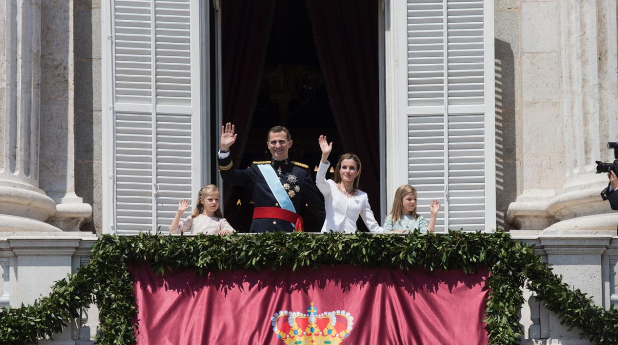 Los Reyes saludan desde el balcón del Palacio Real el día de la proclamación con la Princesa de Asturias y la Infanta Sofía