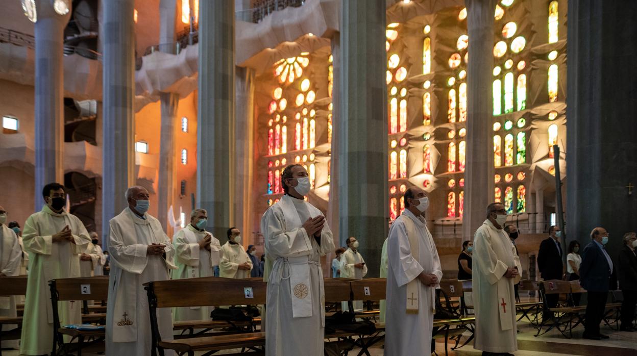 Asistentes protegidos atienden en la celebración de la primera misa en la Catedral de la Sagrada Familia desde el inicio del estado de alarma