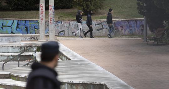 Un policía vigila de lejos a tres menores, en el parque Isabel Clara Eugencia