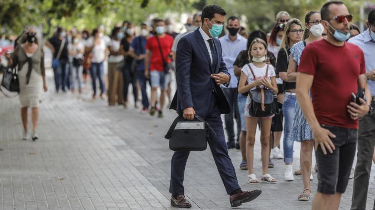 Colas de personas con mascarillas en Valencia, este viernes