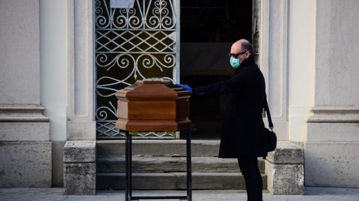 Un hombre junto al féretro de su madre en Bérgamo