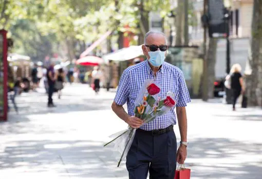 Un hombre pasea, rosas en mano, por el centro de Barcelona