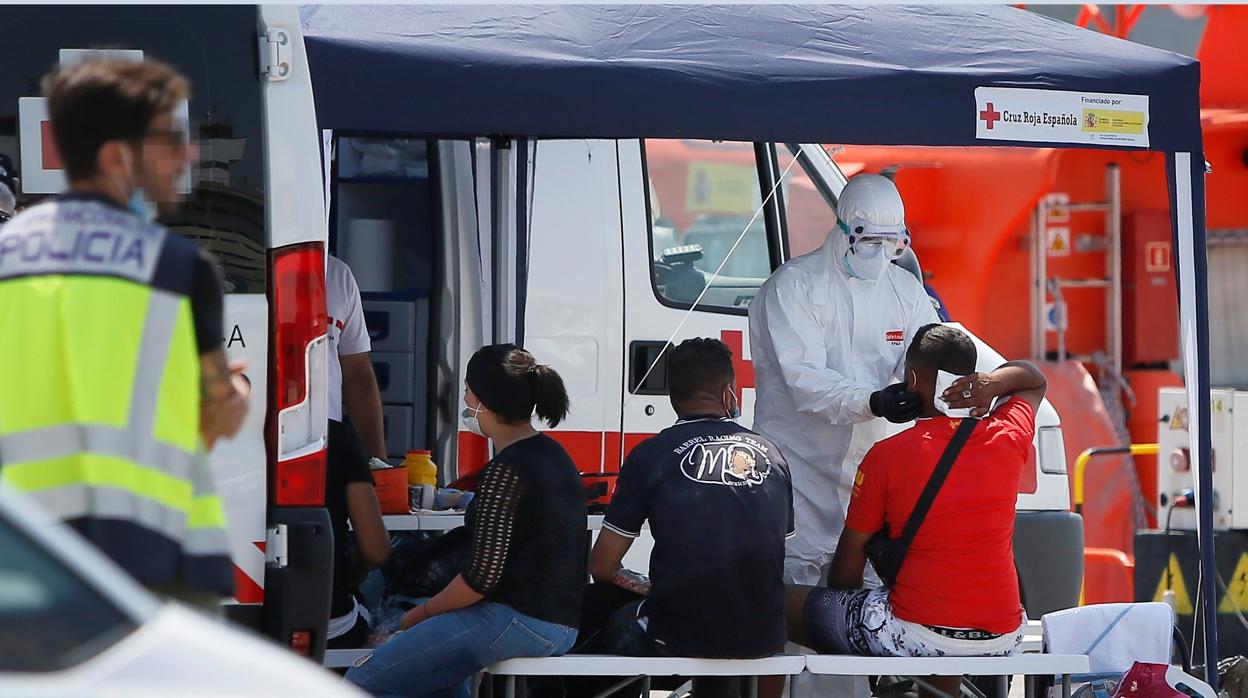 Imagen de los sanitarios de la Cruz Roja, atiendiendo a varios inmigrantes tras alcanzar tierra