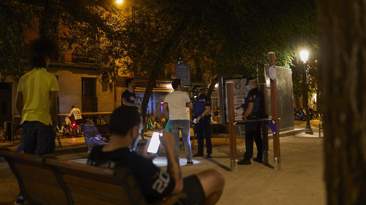 Dos agentes de la Policía Municipal identifican a varios jóvenes en una plaza de la capital