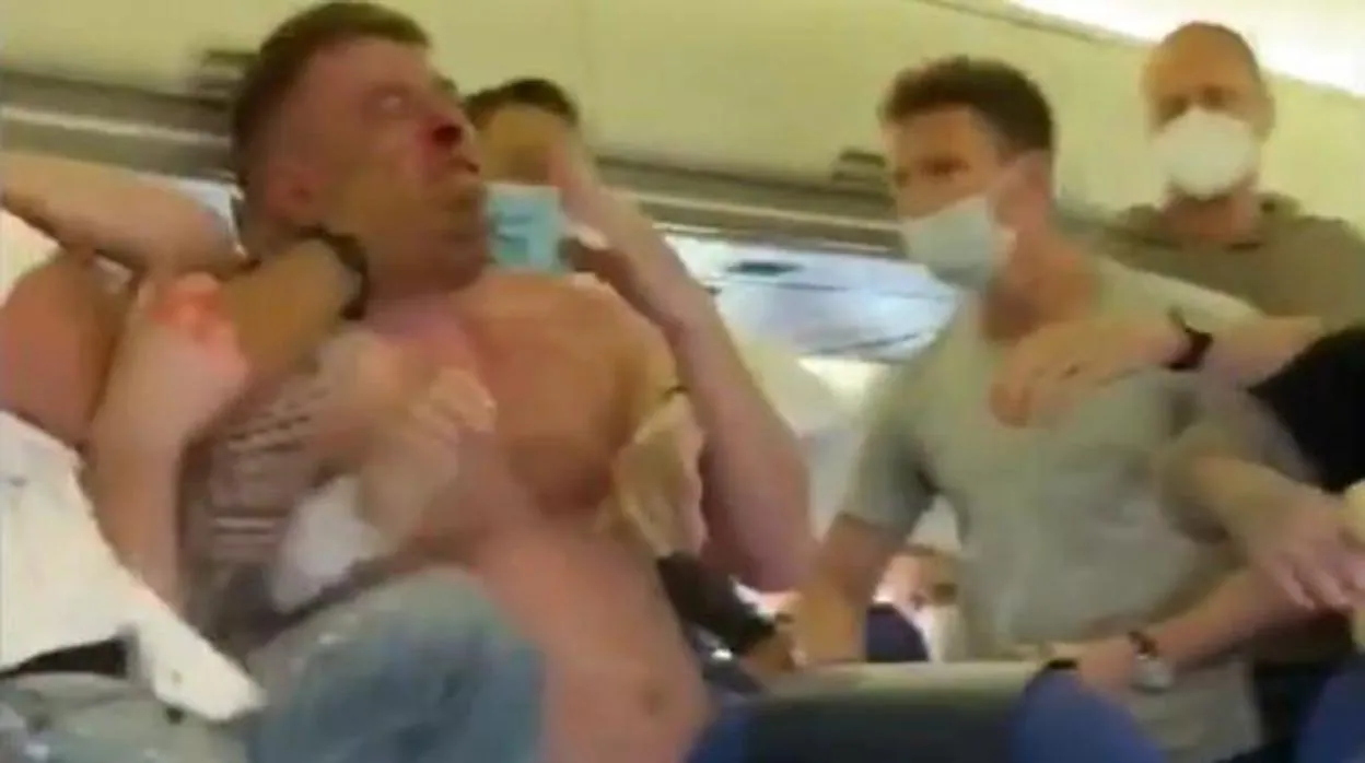 El hombre sin mascarilla es agarrado por un grupo de pasajeros durante la pelea en el avión