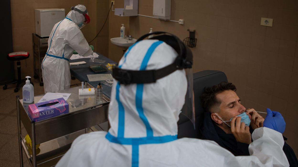 Una profesional sanitaria realiza una prueba PCR a un paciente en el CAP Raval Nord de Barcelona