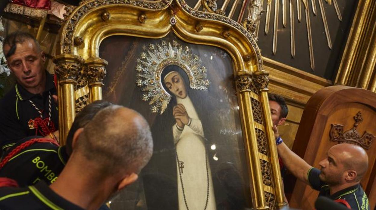 Los bomberos descuelgan el cuadro de la Virgen de La Paloma, el año pasado