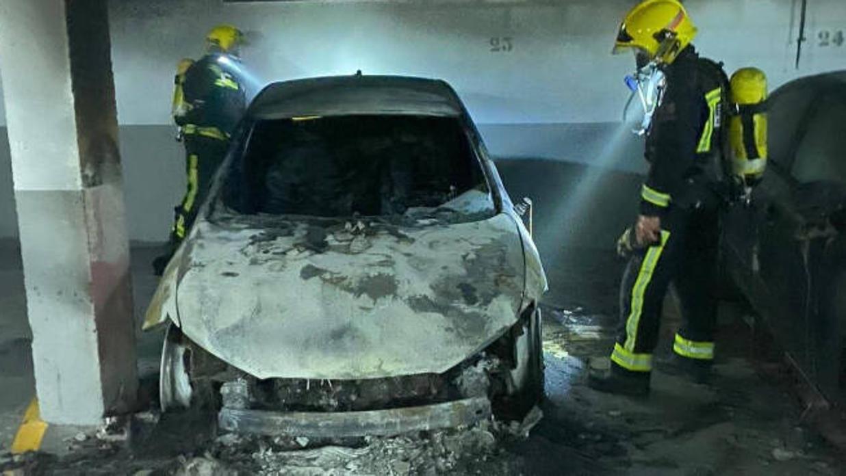 Bomberos de Cuenca, junto a uno de los coches calcinados por el incendio en un garaje de Arcas (Cuenca)