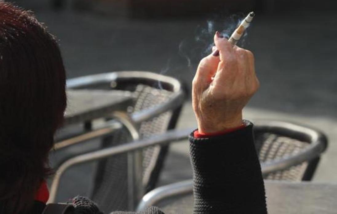 Una mujer se fuma un cigarro en una terraza de un bar