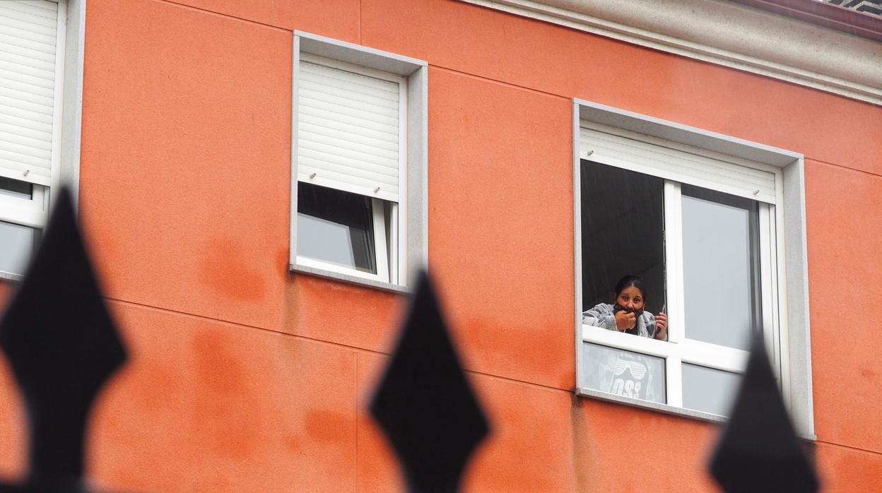 Una mujer se asoma a la ventana del edificio en cuarentena donde se alojan positivos por Covid vinculados al brote de Castro de Rei