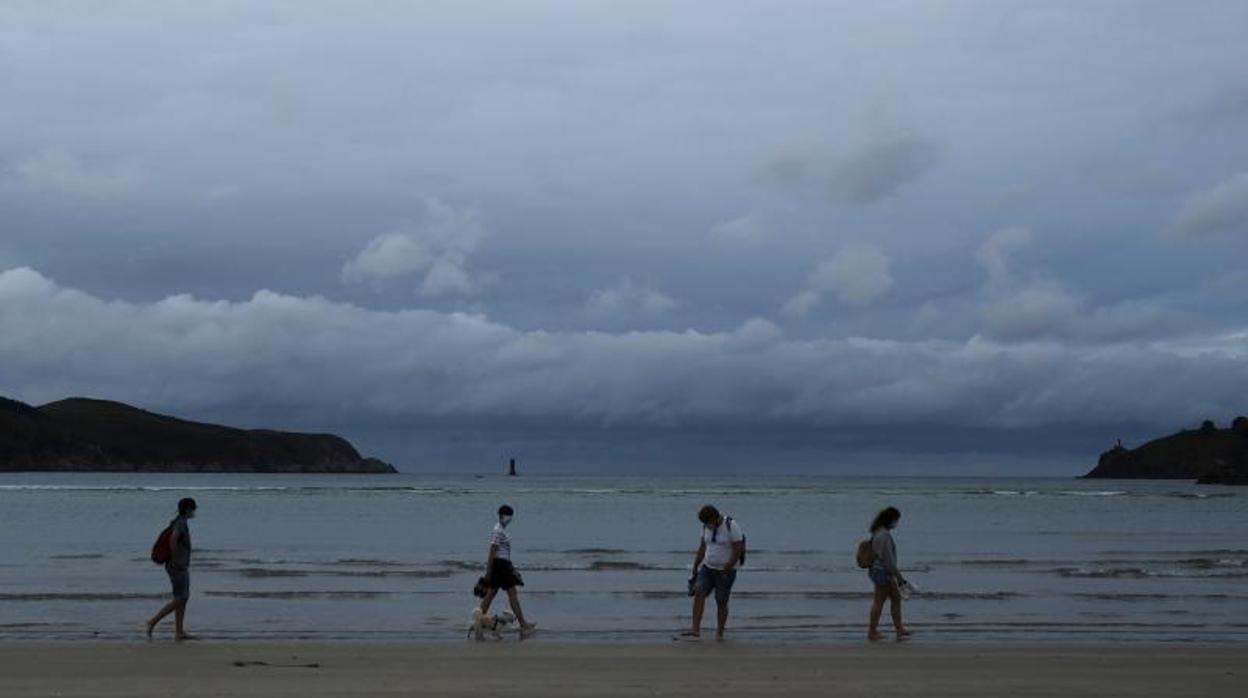 Personas povistas de mascarilla caminan este lunes por una playa de Cedeira, en La Coruña