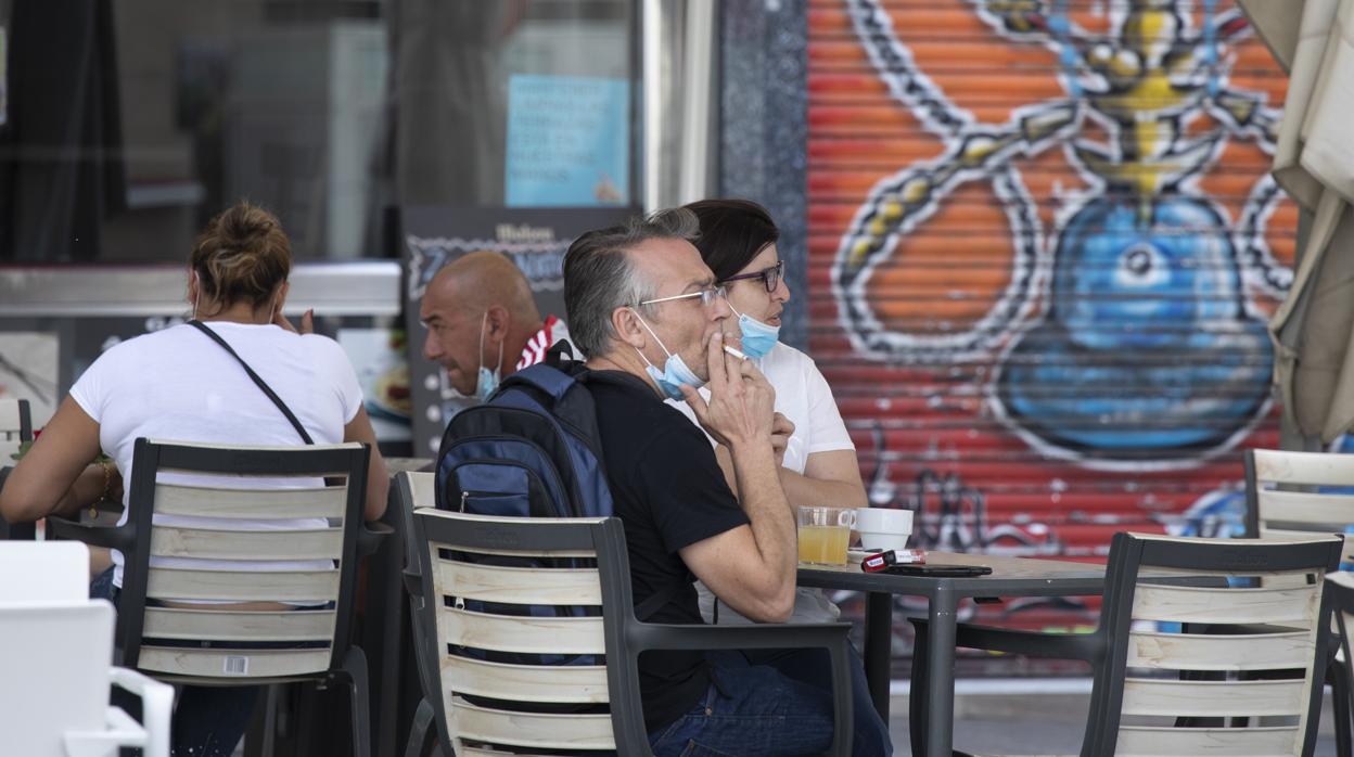 Un hombre fuma un cigarrillo en una terraza de la capital