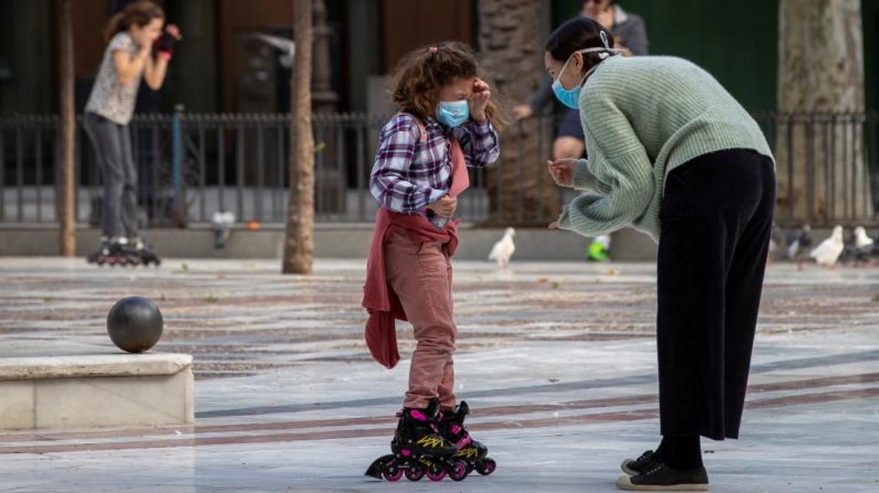 Una niña con mascarilla en un parque público