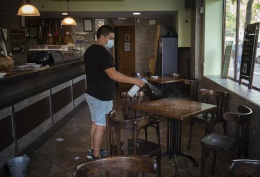 Juan Manuel Rodríguez desinfecta una mesa en el Bar López Bodega