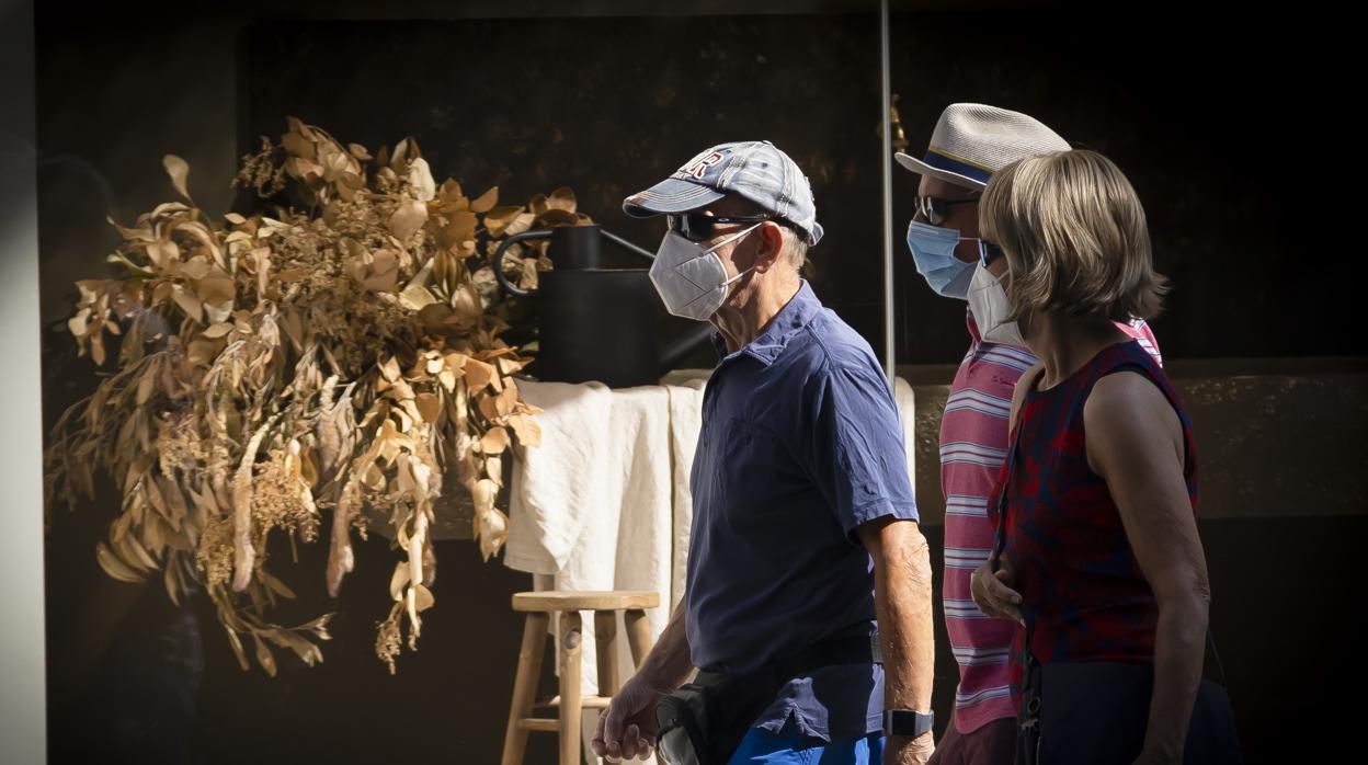 Imagen de tres personas con mascarilla paseando por Alicante