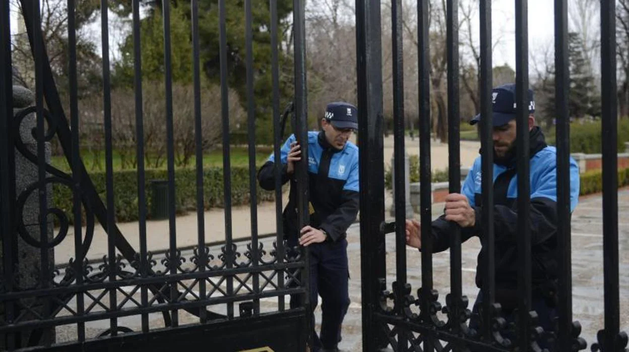 Dos policías municipales cierran las puertas del parque del Retiro