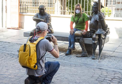 Un turista fotografía a su acompañante junto a la estatua de Don Quijote