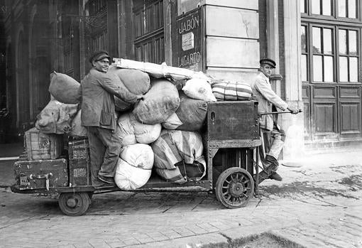 Dos hombres en la antigua estación del Norte manejan una vagoneta eléctrica para el transporte de maletas en 1935