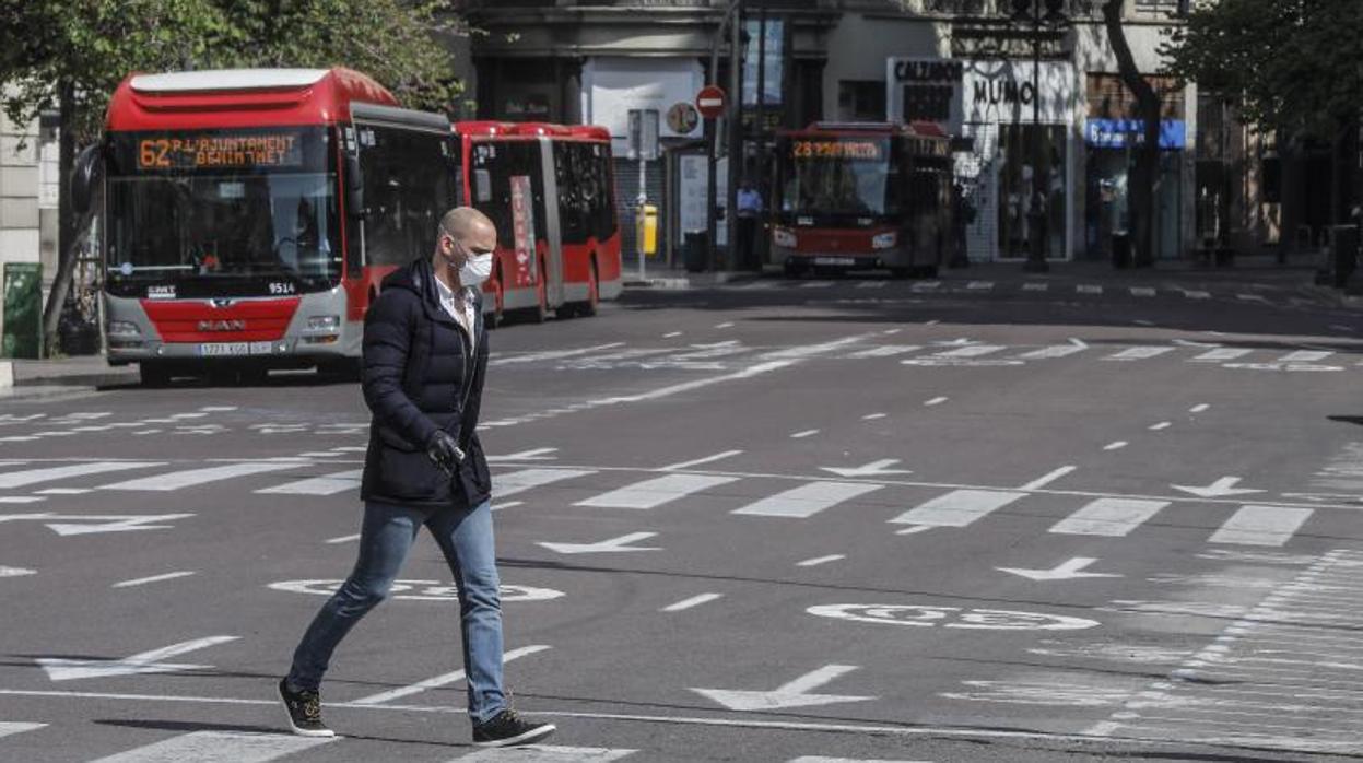 Un hombre pasa delante de autobuses de la EMT en Valencia