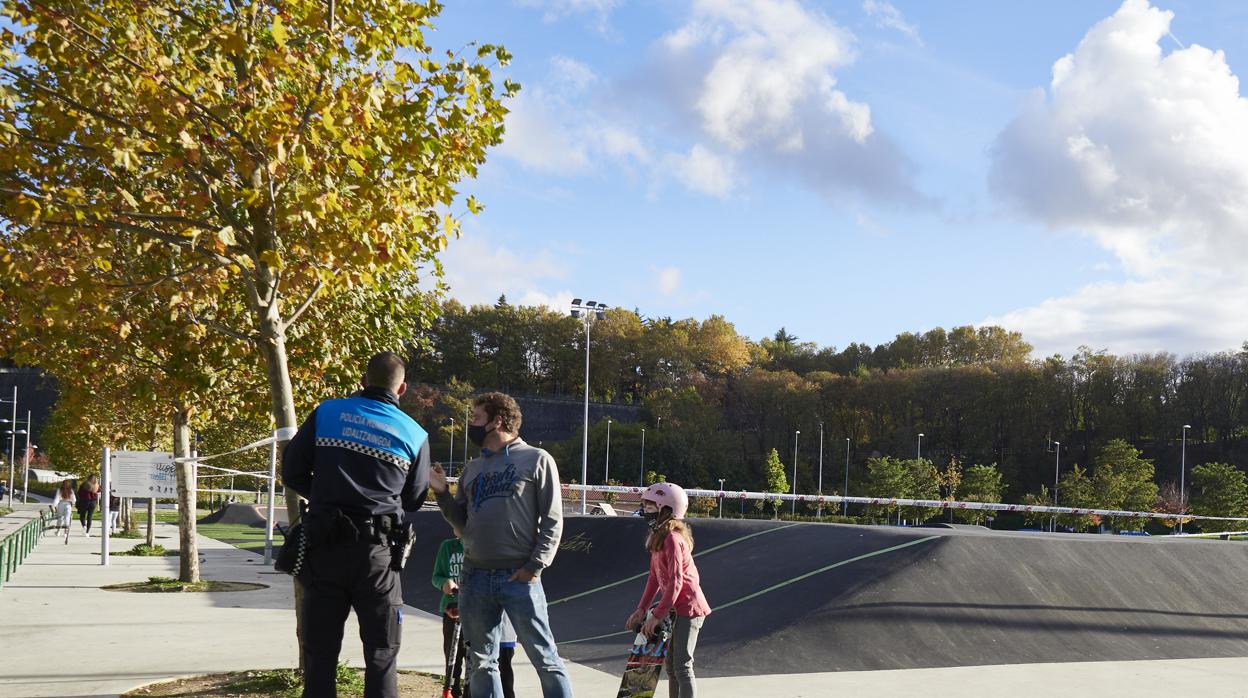 Un Policía Municipal hace indiciaciones a un padre y su hija en un parque de Pamplona