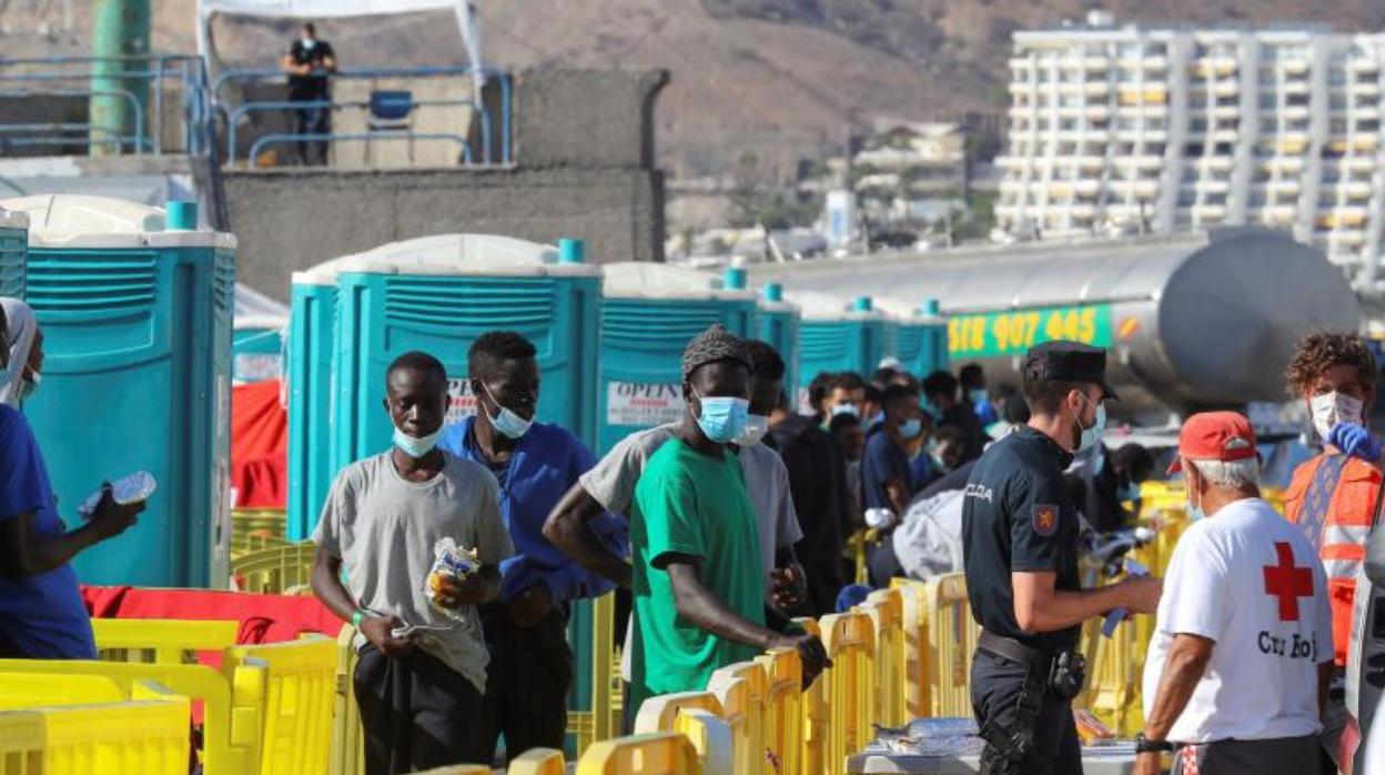 Decenas de inmigrantes hacen cola para conseguir su ración de comida y agua en Arguineguín