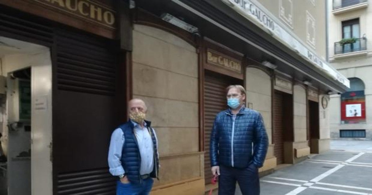 Jesús Ansa del Bar Gaucho de Pamplona con un cliente y amigo, ante el bar con las persianas echadas.