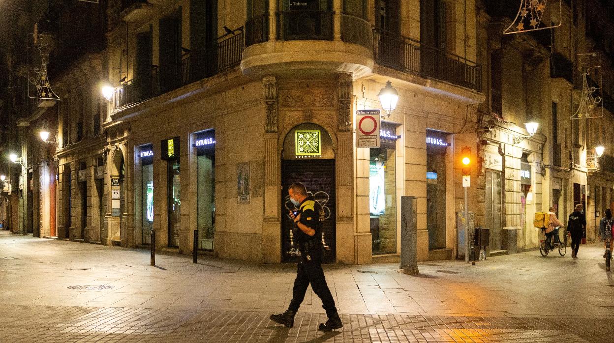 Un agente de la Guardia Urbana patrulla por el centro de Barcelona en la primera noche de toque de queda